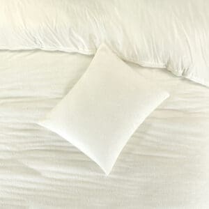 Wit kussen op crèmekleurig bedlinnen